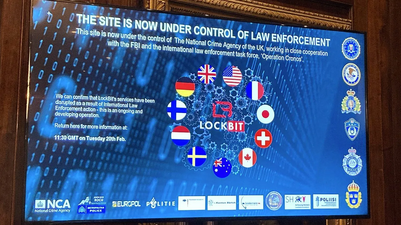 A TV screen shows the front page of LockBit’s dark web leak site that was replaced with the words “this site is now under control of law enforcement,” alongside the flags of the United Kingdom, the U.S. and several other nations during the law enforcement press conference to outline the details of a law enforcement operation against the ransomware syndicate LockBit in London on Feb. 20, 2024.