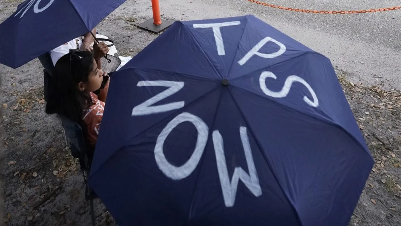 Demonstrators calling for a new designation of Temporary Protected Status for migrants from Nicaragua, El Salvador and Honduras sit in front of the Immigration and Customs Enforcement offices, July 26, 2023, in Miramar, Fla.