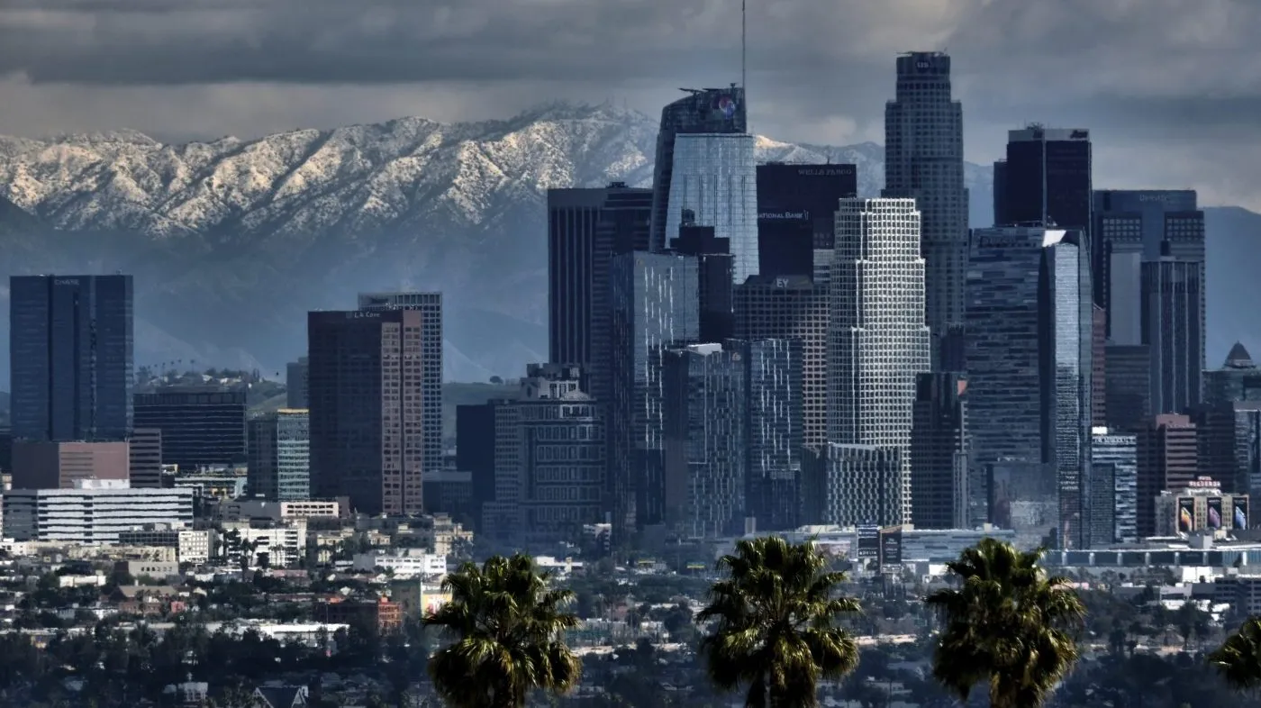 Storm clouds and snowfall are seen over the San Gabriel Mountains behind downtown Los Angeles on Feb. 26, 2023.