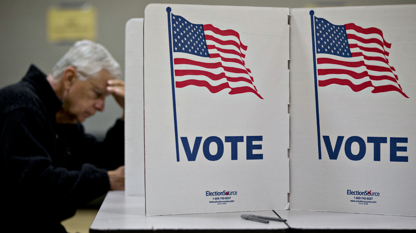 Privacy screens displaying American flags stand near a voter casting a ballot at a polling station in McLean, Virginia, U.S., on Nov. 6, 2018.