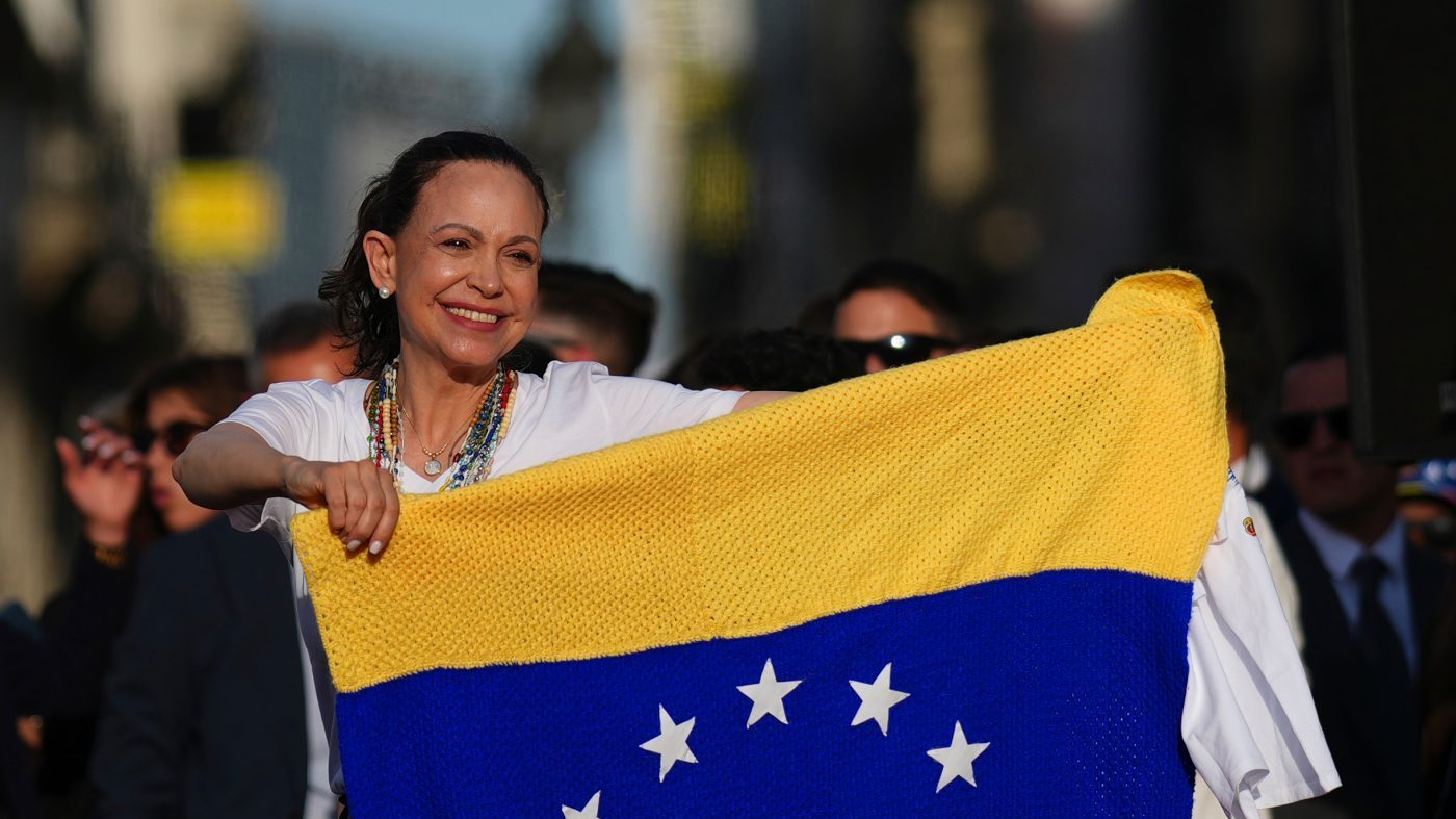 Venezuela’s opposition leader María Corina Machado holds a Venezuelan flag on stage in front of supporters at Madrid’s Puerta del Sol, in Madrid, Spain, on April 18, 2026.