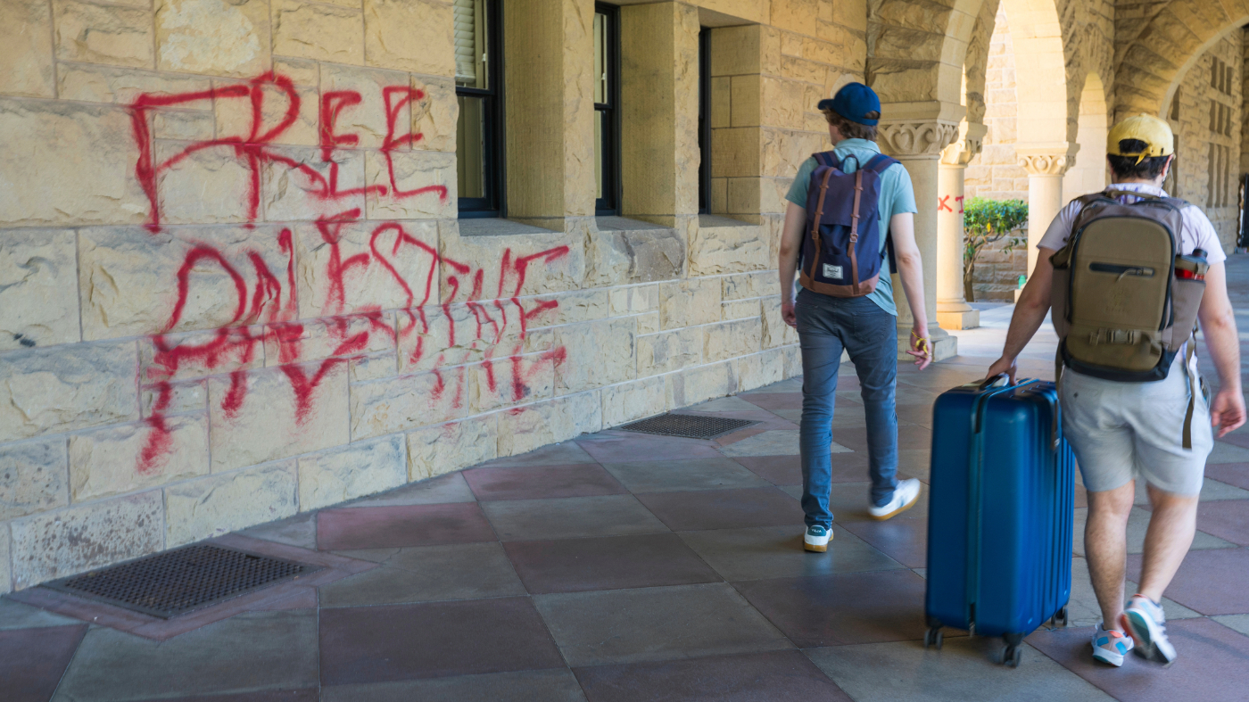 Students walk by graffiti near university president Richard Saller’s office at Stanford University in Palo Alto, Calif., June 5, 2024.