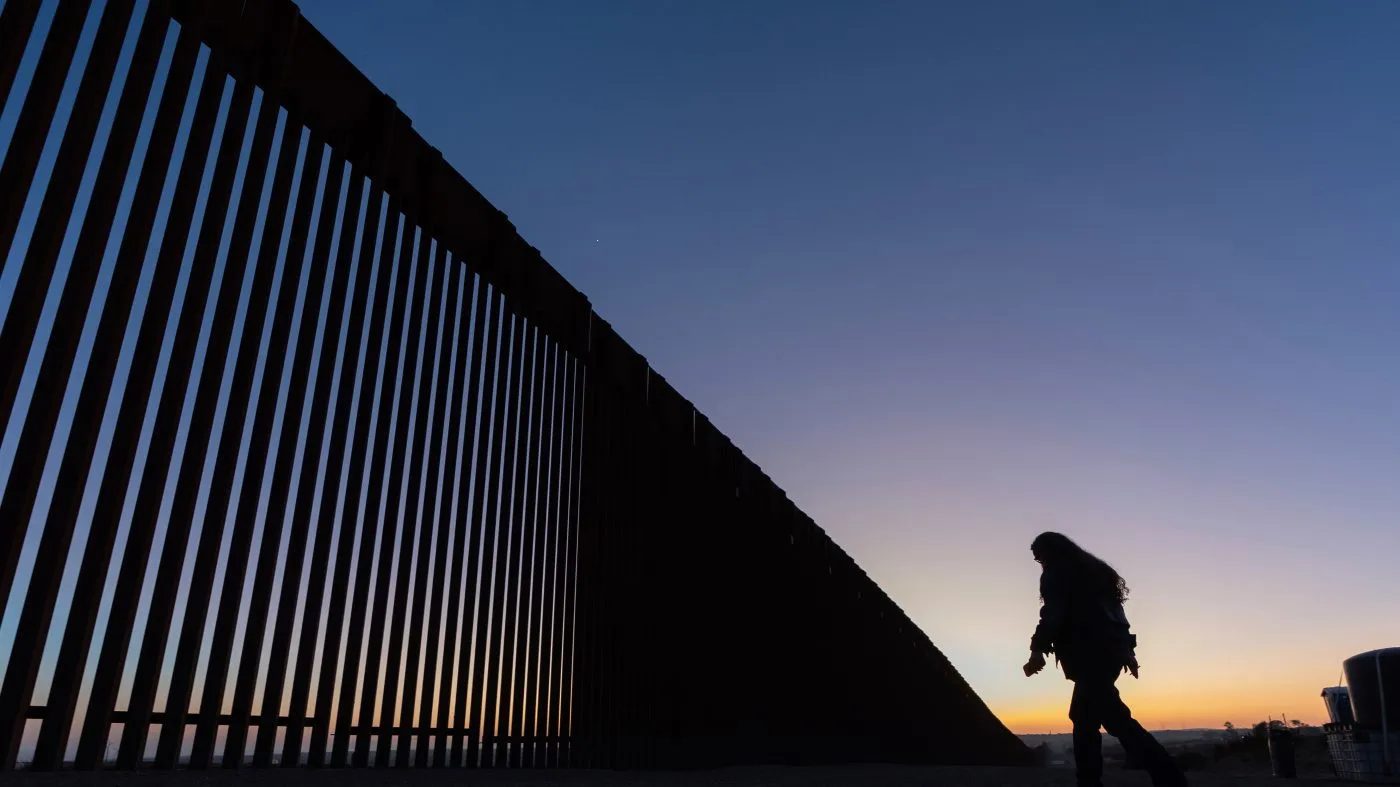 FILE – A volunteer walks along a road next to the border wall separating Mexico and the United States in Jacumba Hot Springs, Calif., Jan. 19, 2025. (AP Photo/Gregory Bull, File)
