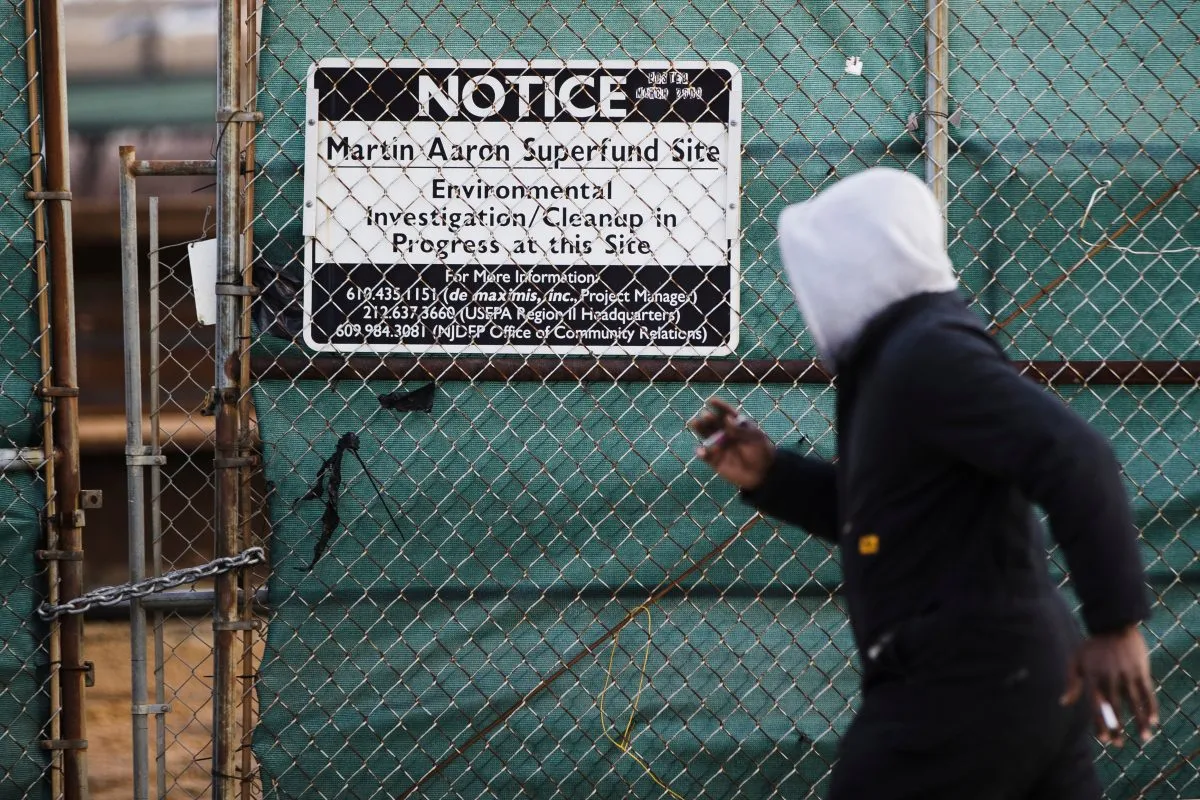 FILE – A man walks past a notice for the Martin Aaron Inc. Superfund site in Camden, N.J., Dec. 11, 2017. (AP Photo/Matt Rourke, File)