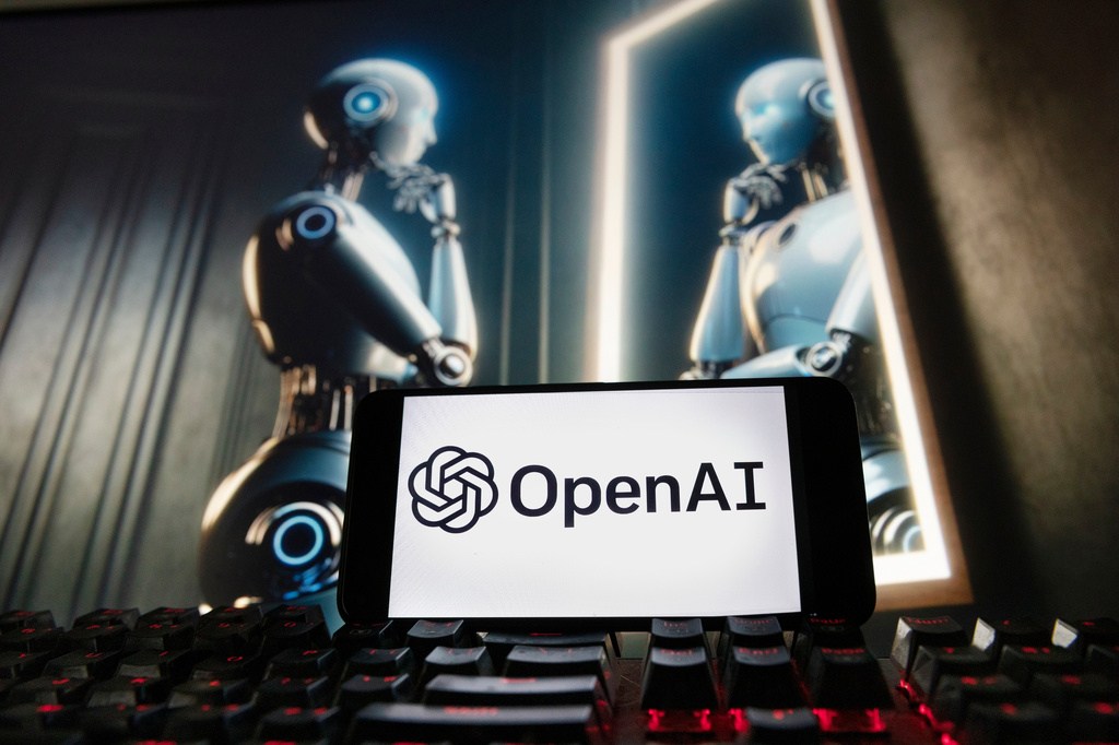 FILE – The OpenAI logo is displayed on a cellphone with an image on a computer monitor generated by ChatGPT’s Dall-E text-to-image model, Dec. 8, 2023, in Boston. (AP Photo/Michael Dwyer, File)