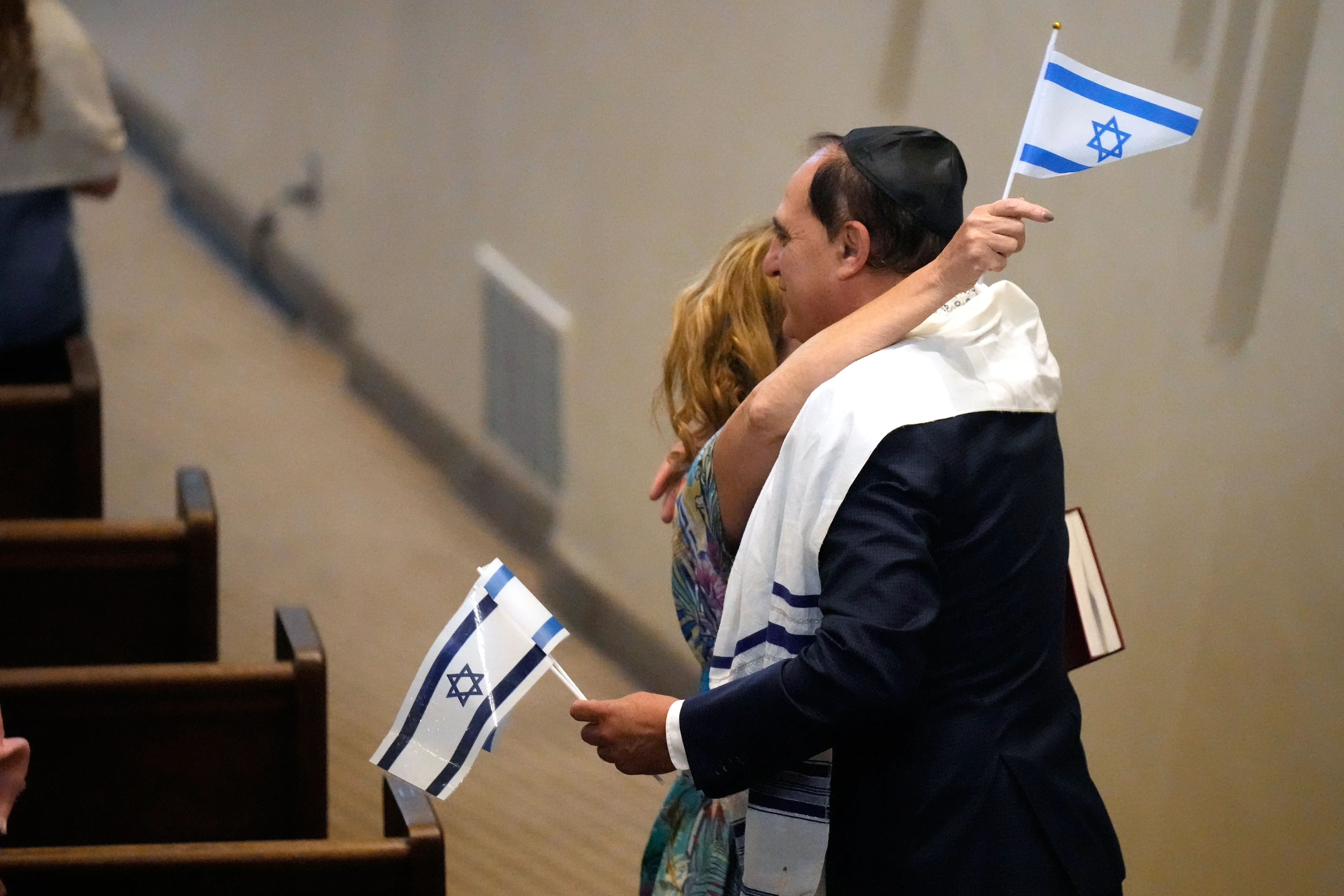 FILE – People hold Israeli flags as they hug during Shabbat Services at The Sinai Temple in Los Angeles, Oct. 14, 2023. (AP Photo/Damian Dovarganes, File)