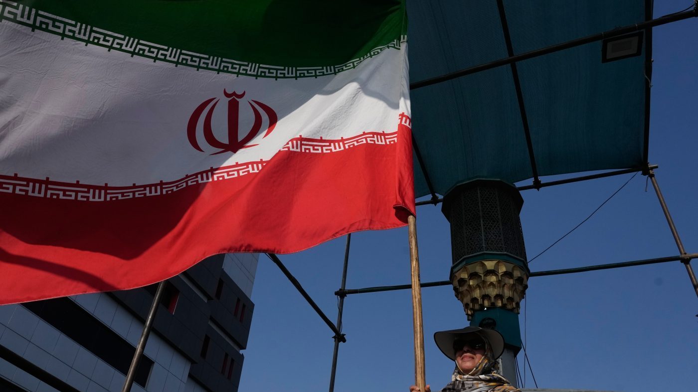A woman holds an Iranian flag as part of a pro-government campaign in downtown Tehran, Iran, Aug. 17, 2026.