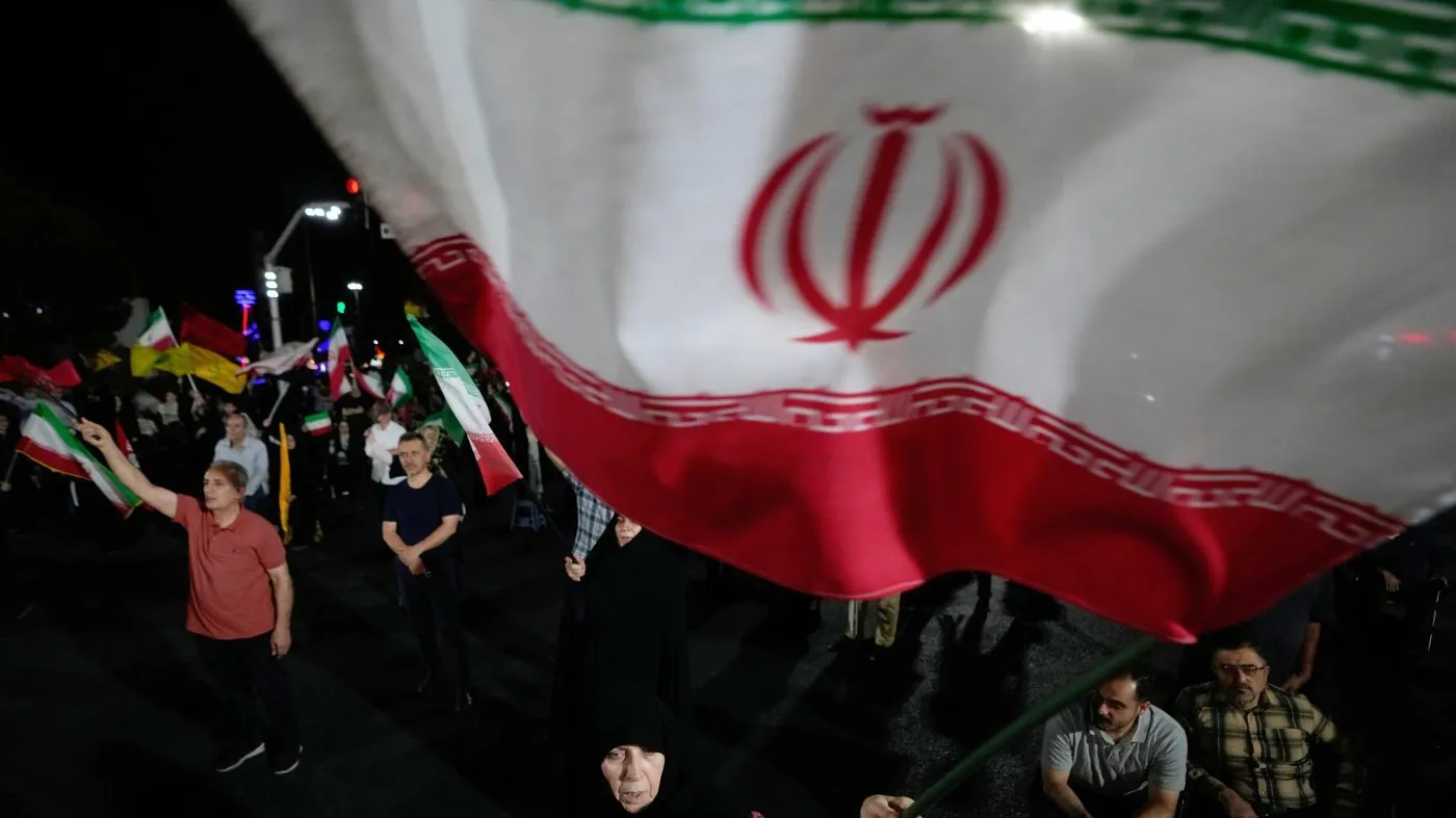 A pro-government demonstrator waves an Iranian flag during a gathering in a square in Tehran, Iran, Wednesday, Aug. 26, 2026. (AP Photo/Vahid Salemi)
