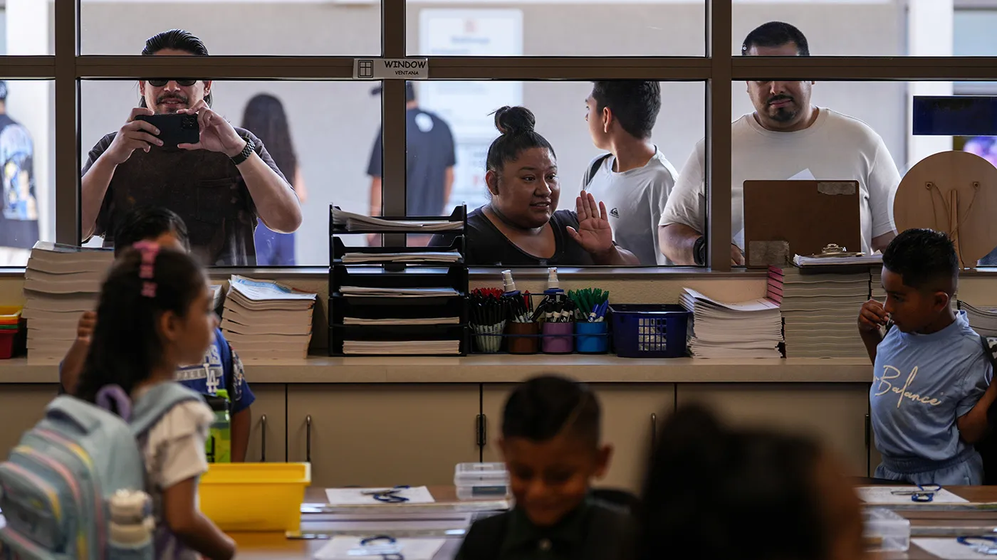 Parents watch their children through a classroom window on the first day of school at Betsy Ross Elementary School in Anaheim, Calif., Aug. 6, 2026.