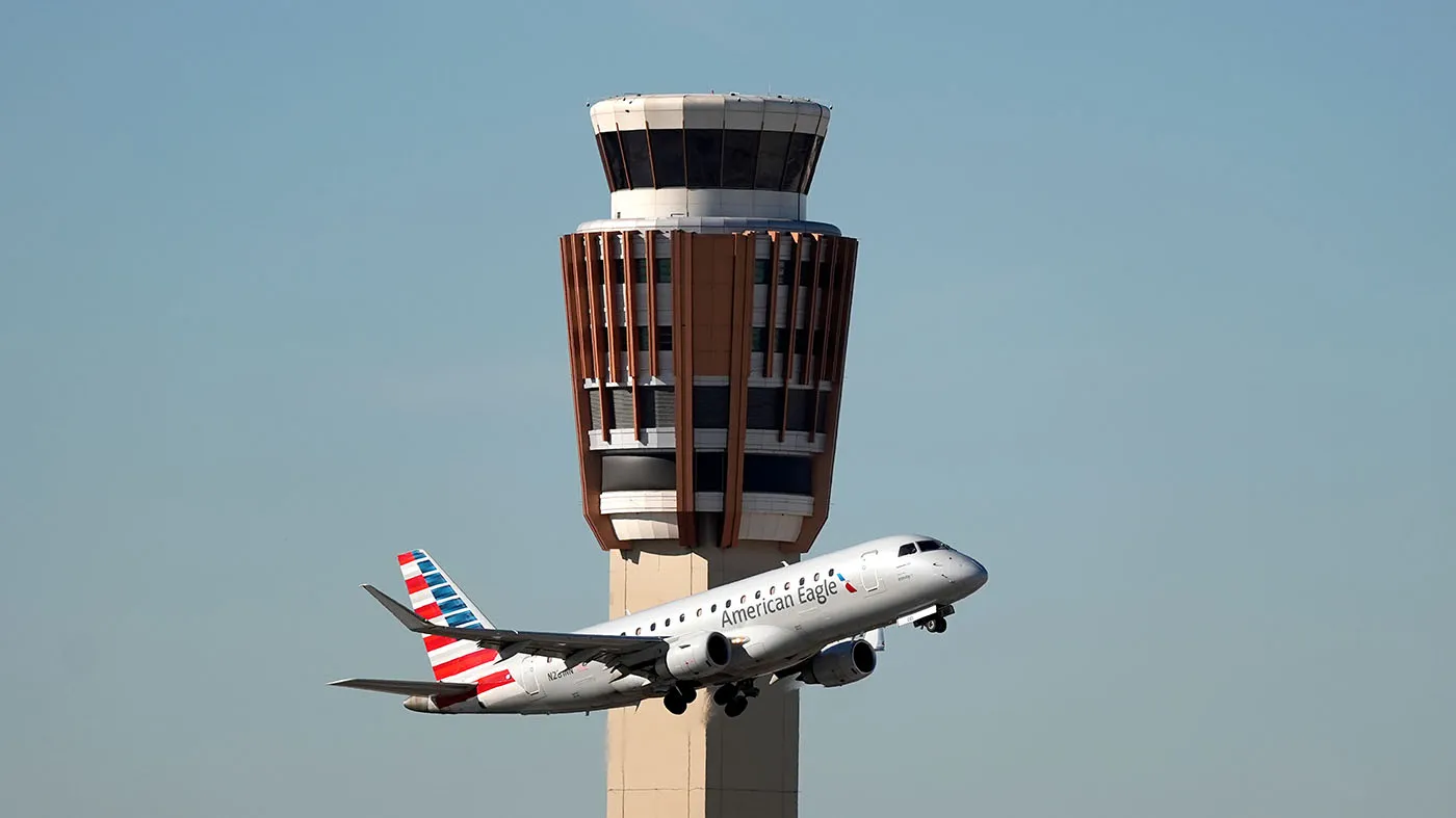 An American Airlines American Eagle jet flies past the air traffic control tower at Phoenix Sky Harbor International Airport on Nov. 8, 2025, in Phoenix.