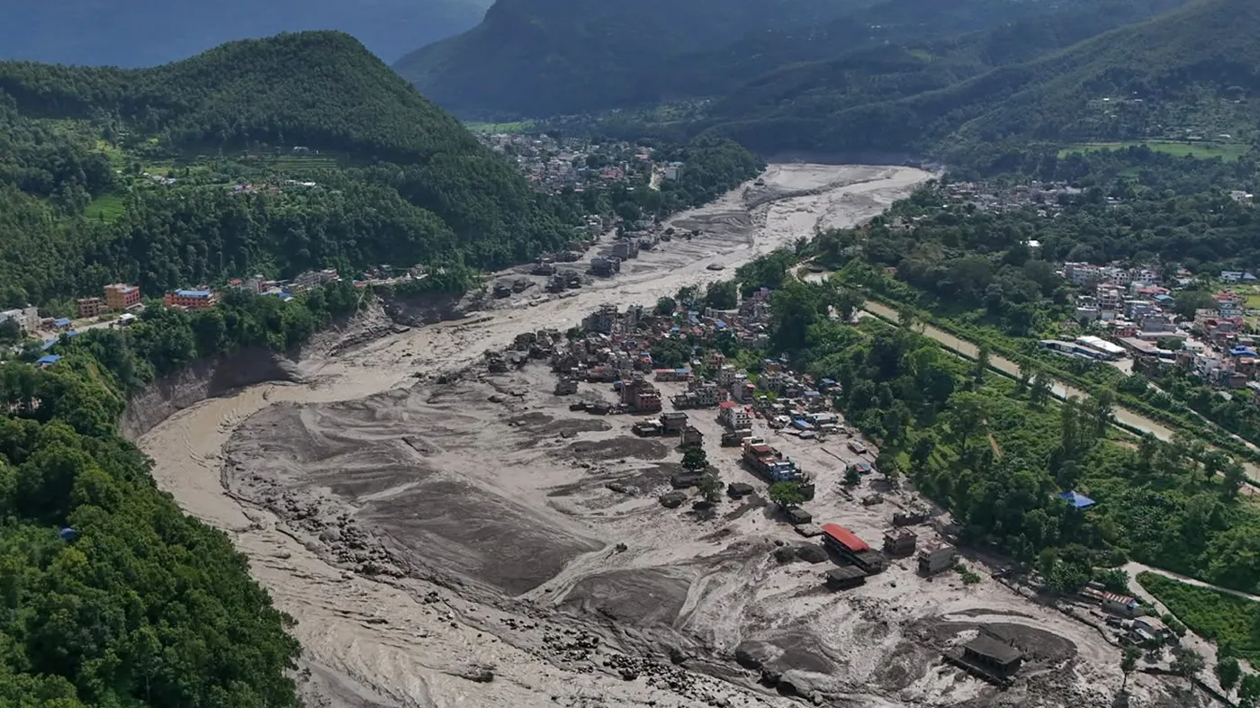 Damaged houses stand precariously near the swollen, debris-choked banks of the Trishuli River after flash floods in Nepal’s Nuwakot district on Aug. 26, 2026.