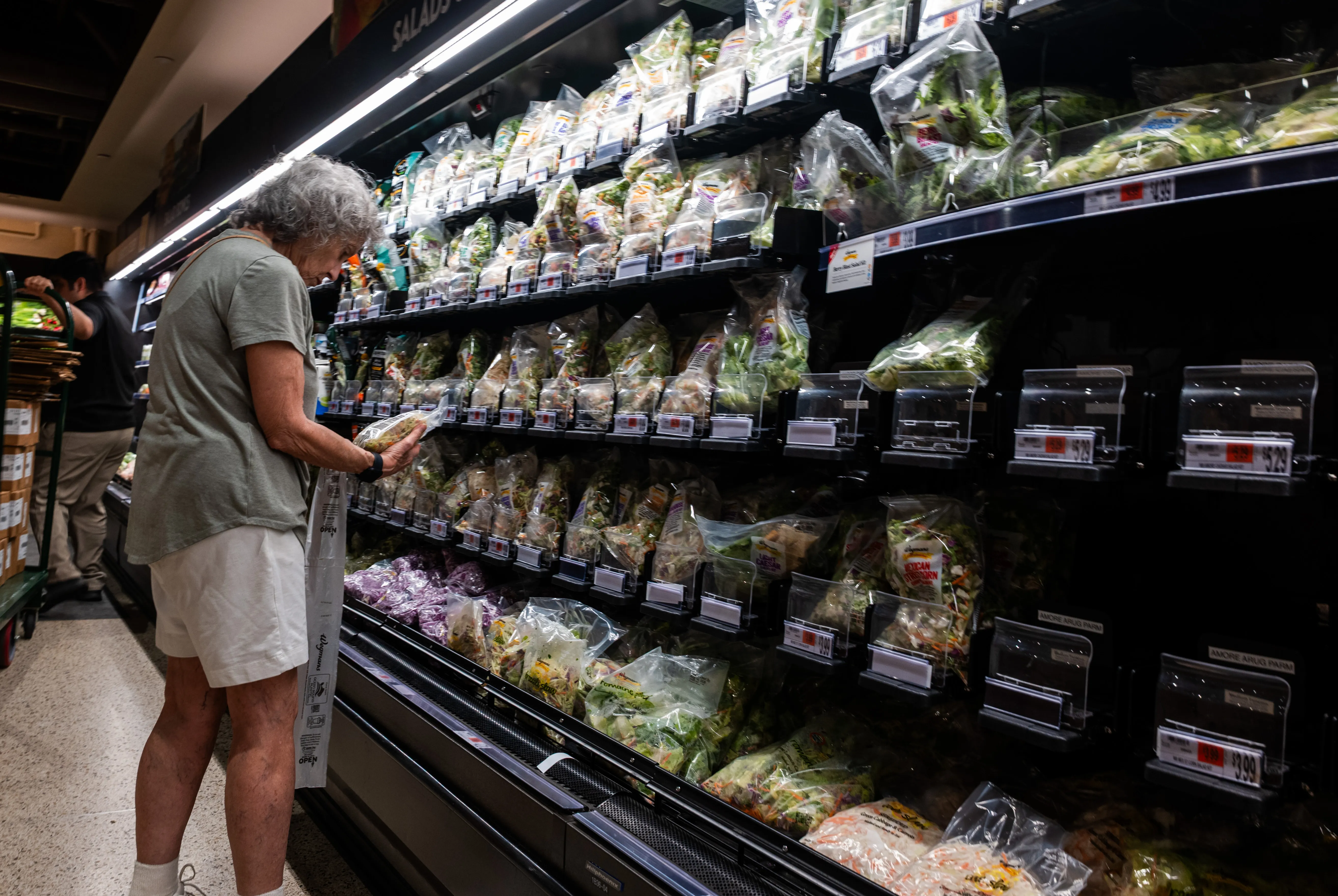 NEW YORK, NEW YORK – AUGUST 13: A customer examines salad and lettuce displayed on the shelf of a Manhattan grocery store on August 13, 2026, in New York City. New government data show that lettuce prices plunged 16.4% from June to July, as a Cyclospora outbreak continues to spook shoppers. The outbreak, which causes nausea and diarrhea, has been tied to iceberg lettuce from a Taylor Farms facility in Mexico. (Photo by Spencer Platt/Getty Images)