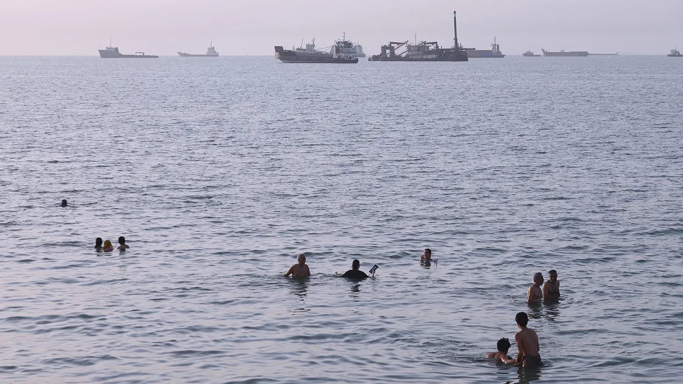 Residents swim as cargo and commercial vessels are anchored in the Strait of Hormuz off Bandar Abbas, Iran, on Aug. 6, 2026.