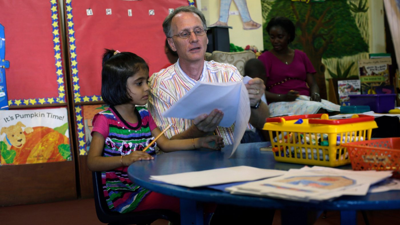 In this picture taken Monday Nov. 10, 2014, Tim Casey engages with pupils at the American International School he runs in Conakry, Guinea. (AP Photo/Jerome Delay)