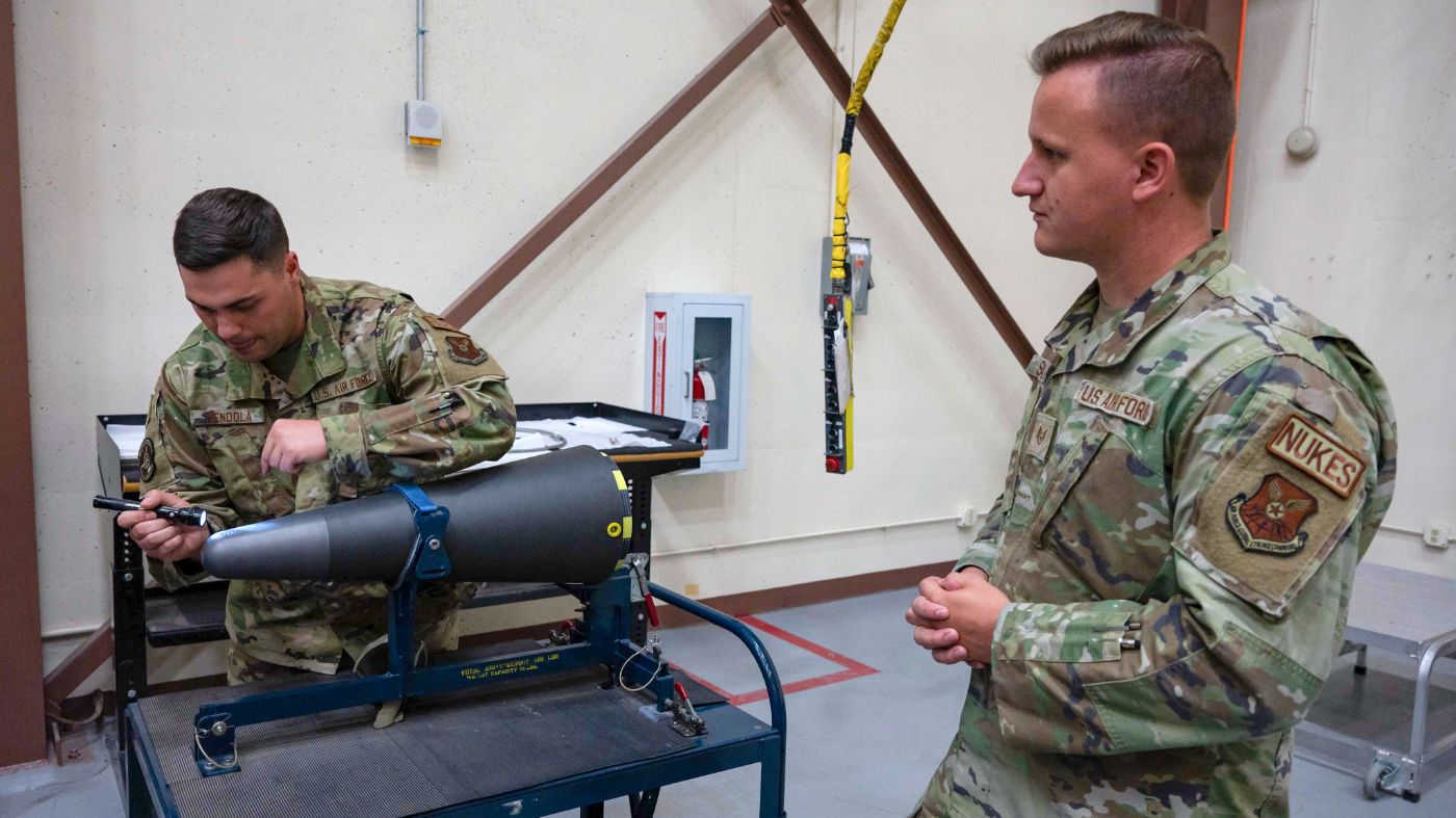 In this image provided by the U.S. Air Force, Staff Sgt. Brandon Mendola, left, with the 90th munitions squadron at F.E. Warren Air Force Base in Wyoming demonstrates how they train new missile maintainers to look for scratches on the top of a nuclear warhead. (Senior Airman Sarah Post/U.S. Air Force via AP)
