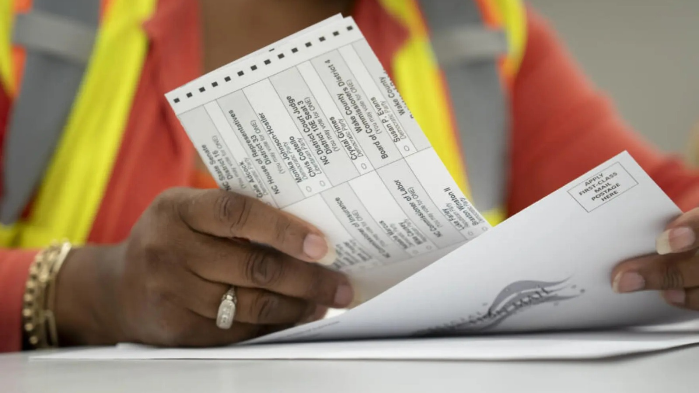 Election workers prepare mail-in ballots.