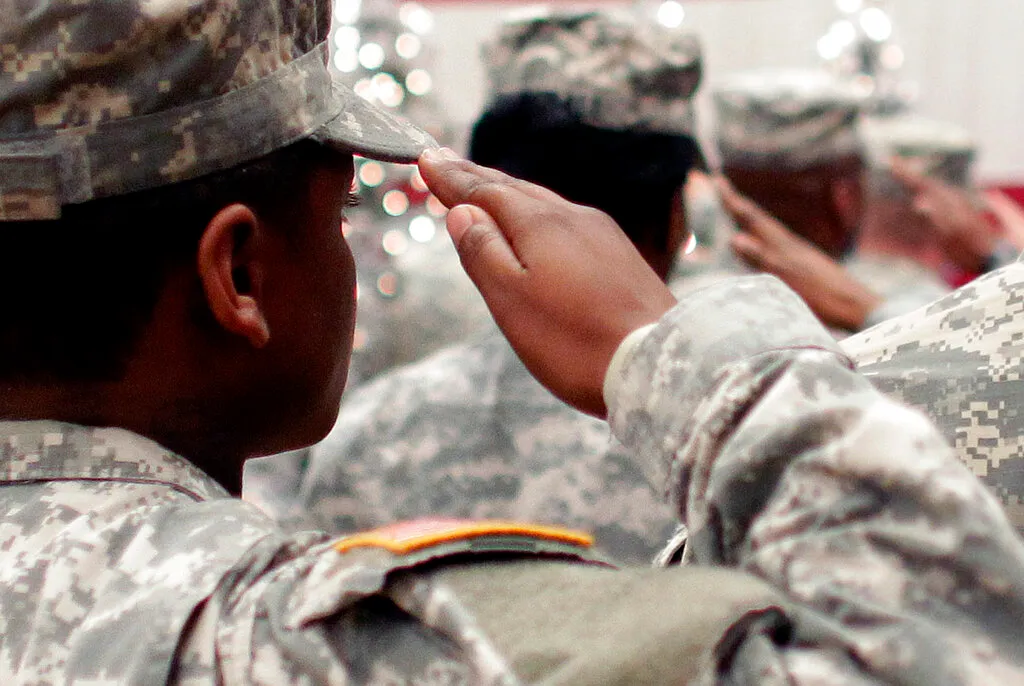 FILE – In this Wednesday Dec. 5, 2012, file photo, soldiers salute the U.S. flag during the Pledge of Allegiance at a welcome home ceremony for soldiers returning from a deployment in Afghanistan, at Fort. Carson, Colo. For veterans, the GI Bill can be the ticket to a debt-free college education. (AP Photo/Brennan Linsley, File)