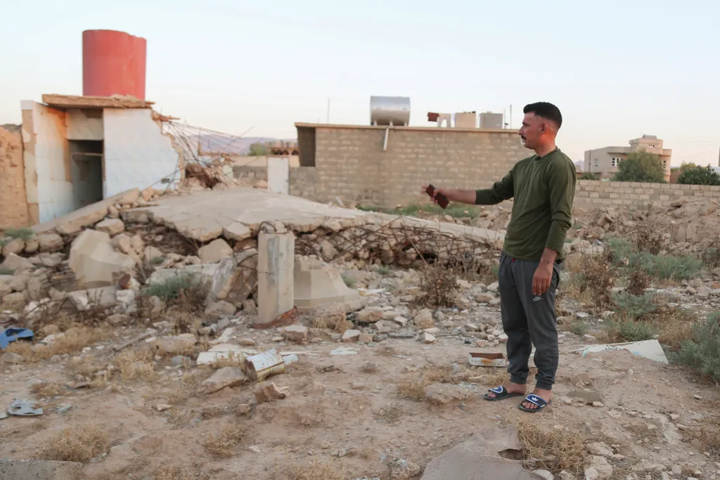 Hadi Shammo, 30, a Yazidi returnee, stands amid the wreckage of his destroyed family house in the village of Dugure in Sinjar, Iraq, Tuesday, July 16, 2024. “In the end we have to return here — our life is here” in Sinjar, said Shammo, whose family returned from a camp in Duhok area. “This is part of our identity.” (AP Photo/Farid Abdulwahed)