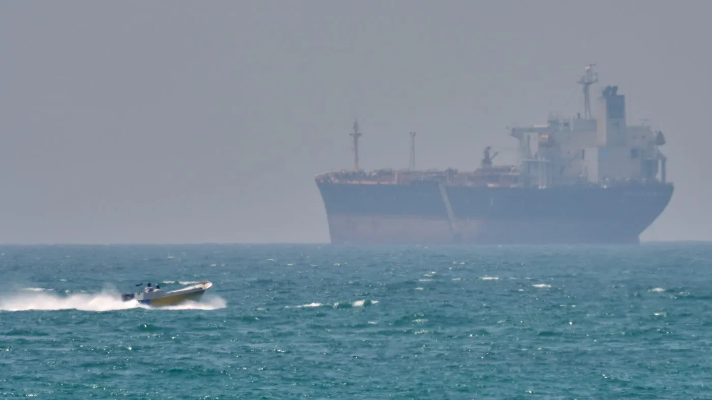 FILE – A boat sails past a tanker anchored on the Strait of Hormuz off the coast Qeshm island, Iran, April 18, 2026. (AP Photo/Asghar Besharati, File)