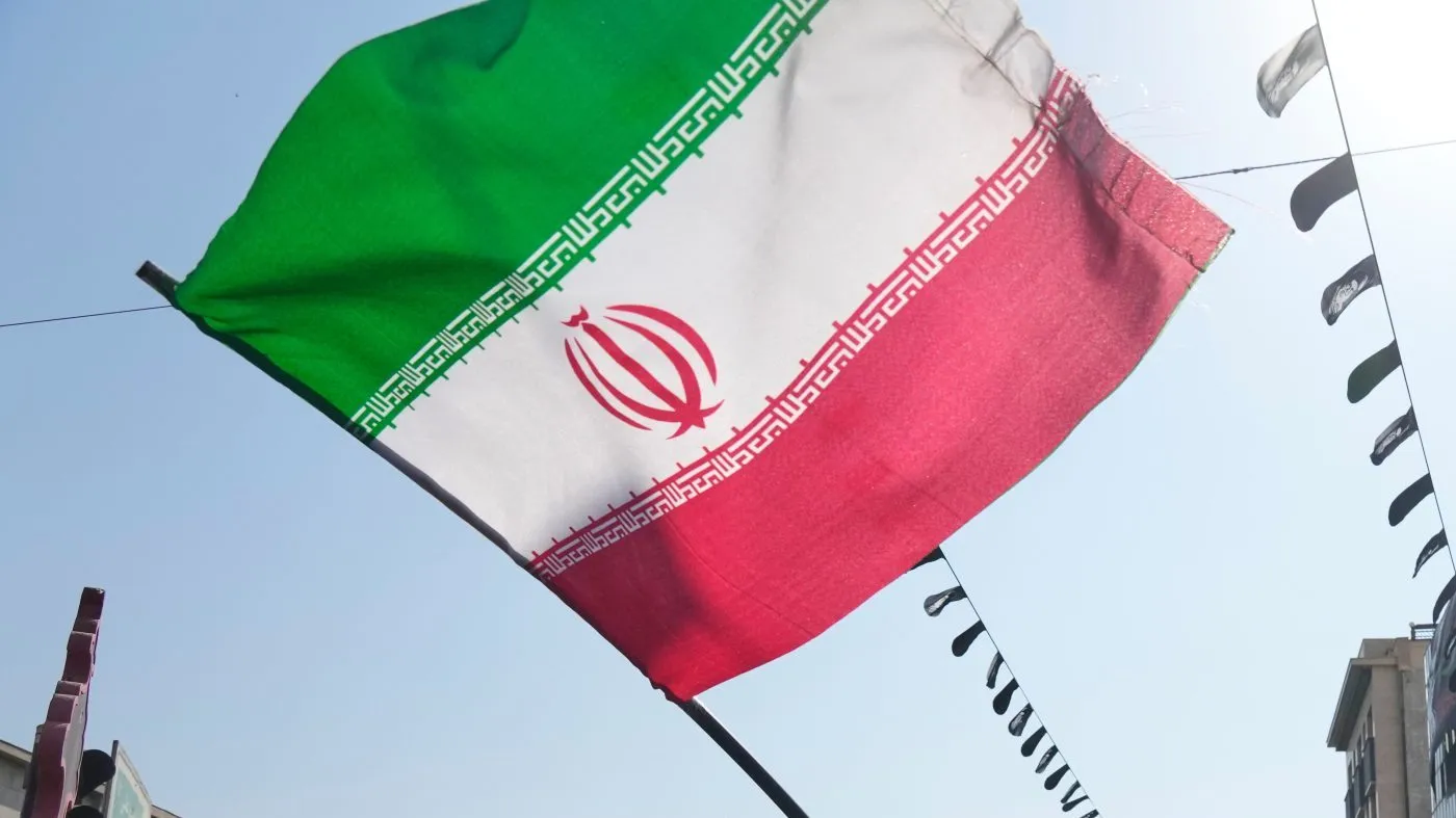 A woman waves an Iranian flag as a banner showing a portrait of the late Supreme Leader Ayatollah Ali Khamenei is seen at rear during Arbaeen rituals, which is held 40 days after Ashoura, commemorating the killing of the grandson of the Prophet Muhammad Imam Hussein and members of his family at the Battle of Karbala in 680 A.D. in Tehran, Iran, Tuesday, Aug. 4, 2026. (AP Photo/Vahid Salemi)