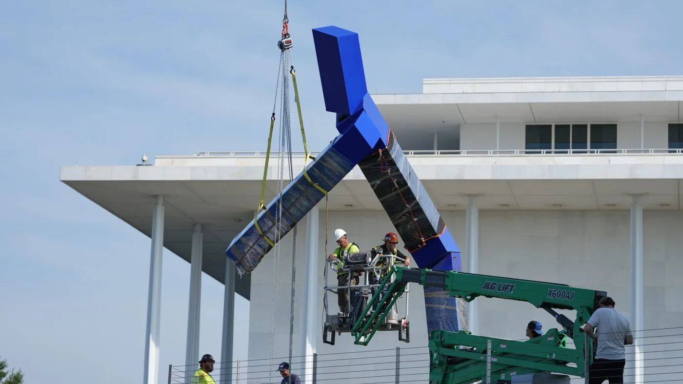 Workers remove the sculpture “Blue” by artist Joel Shapiro on the grounds of the John F. Kennedy Center for the Performing Arts in Washington, Wednesday, Sept. 2, 2026. (AP Photo/Mark Schiefelbein)