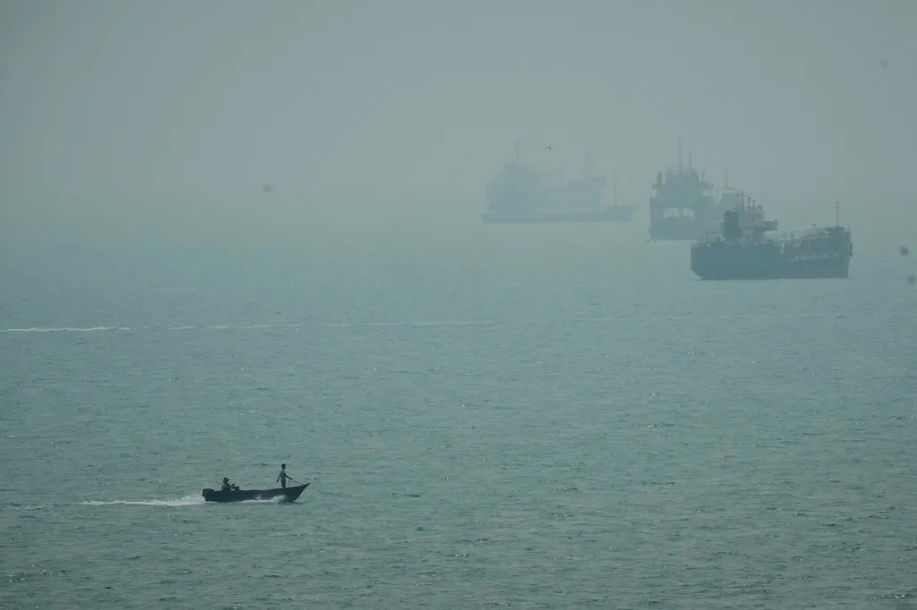 A motorboat travels past commercial vessels anchored amid haze in the Strait of Hormuz off Bandar Abbas, Iran, Monday, Sept. 7, 2026. (AP Photo/Vahid Salemi)