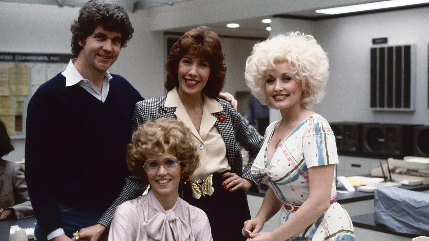 Portrait of, from left, Australian-American film director Colin Higgins (1941 – 1988), and American actors Jane Fonda (fore), Lily Tomlin (in checked blazer), and Dolly Parton on the set of the film ‘9 to 5’ (also known as ‘Nine to Five,’ directed Higgins), Los Angeles, California, 1979. (Photo by Steve Schapiro/Corbis via Getty Images)