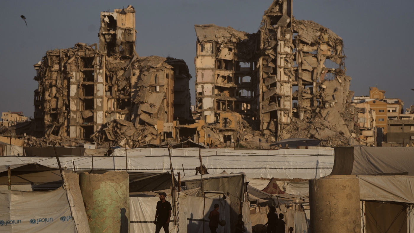 People walk past tents sheltering displaced Palestinians amid the ruins of buildings destroyed by Israeli airstrikes during the war with Hamas, in Gaza City, Monday, Aug. 17, 2026. (AP Photo/Jehad Alshrafi)