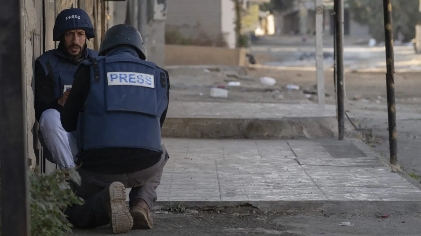 Journalists take cover from gunfire as Palestinian security forces mount a major raid against militants in the Jenin refugee camp in the Israeli-occupied West Bank, Dec. 23, 2024.