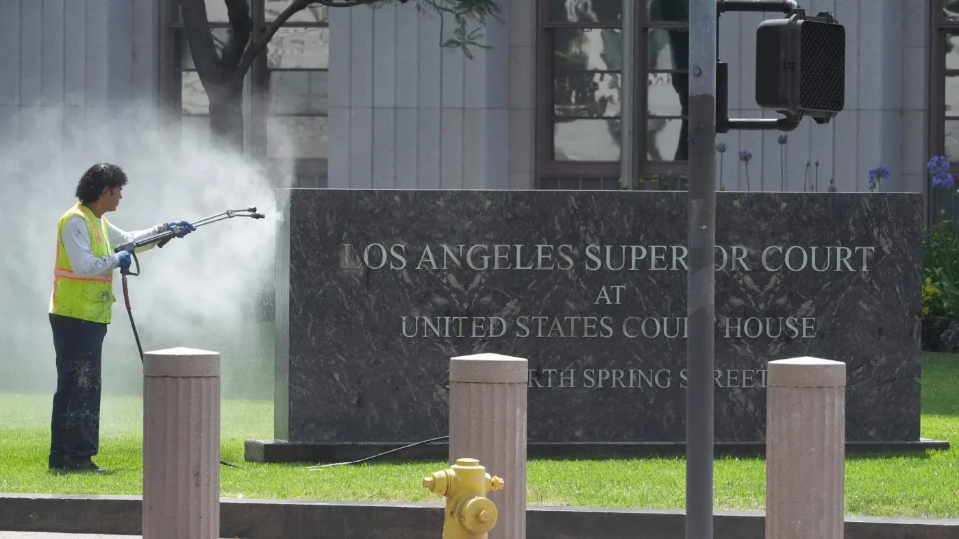 A man pressure washes the sign for the Superior Court on June 10, 2025, in Los Angeles.