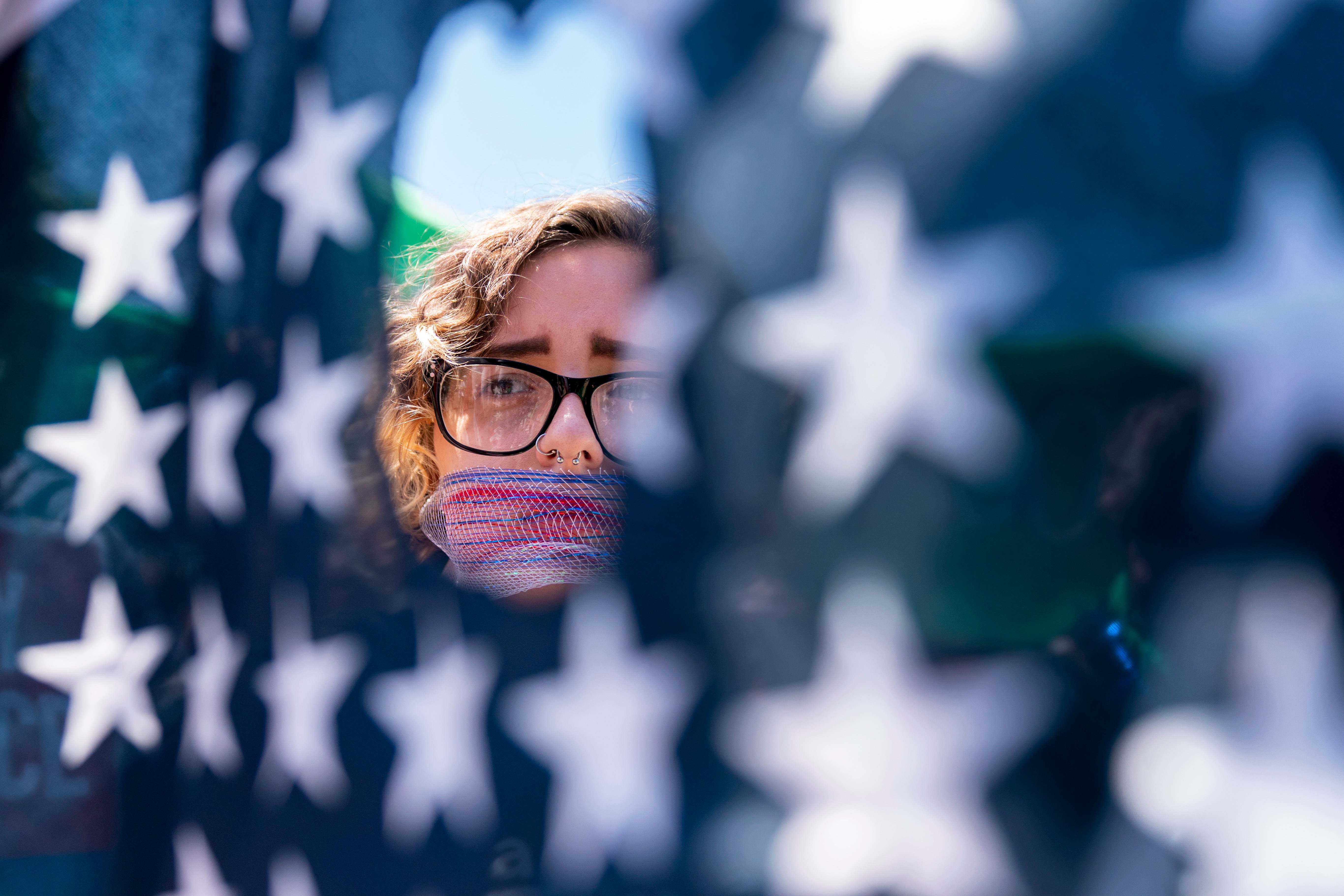 FILE – Emma Rousseau of Oakland, N.J., her mouth bound with a red, white and blue netting, attends a rally on the Fourth of July to protest for abortion rights, at Lafayette Park in front of the White House in Washington, July 4, 2022. (AP Photo/Andrew Harnik, File)