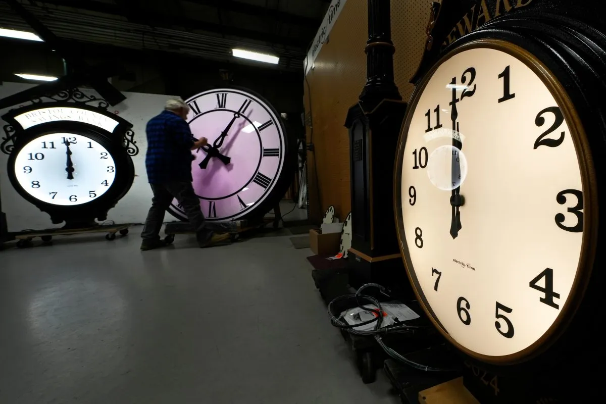 FILE – Clockmaker Scott Gow adjusts the hands of a clock at the Electric Time Company, Oct. 30, 2024, in Medfield, Mass. (AP Photo/Charles Krupa, File)
