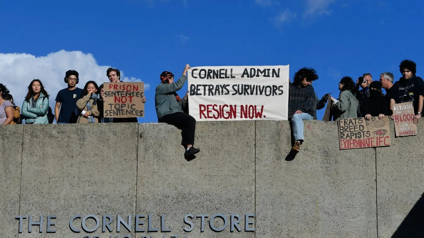 Attendees hold signs during a protest against Cornell University’s handling of the 2024 fraternity-house gang rape allegations at the university Monday, Oct. 5, 2026, in Ithaca, N.Y. (AP Photo/Adrian Kraus)