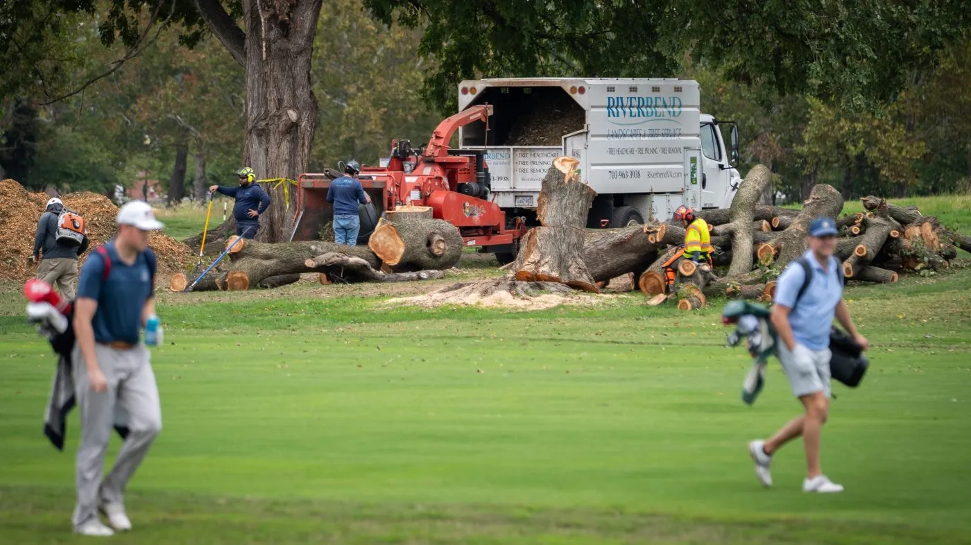 Golfers pass workers as the National Park Service begins cutting down trees at East Potomac Golf Links, Saturday, October 10, 2026, in Washington. (AP Photo/Nathan Howard)