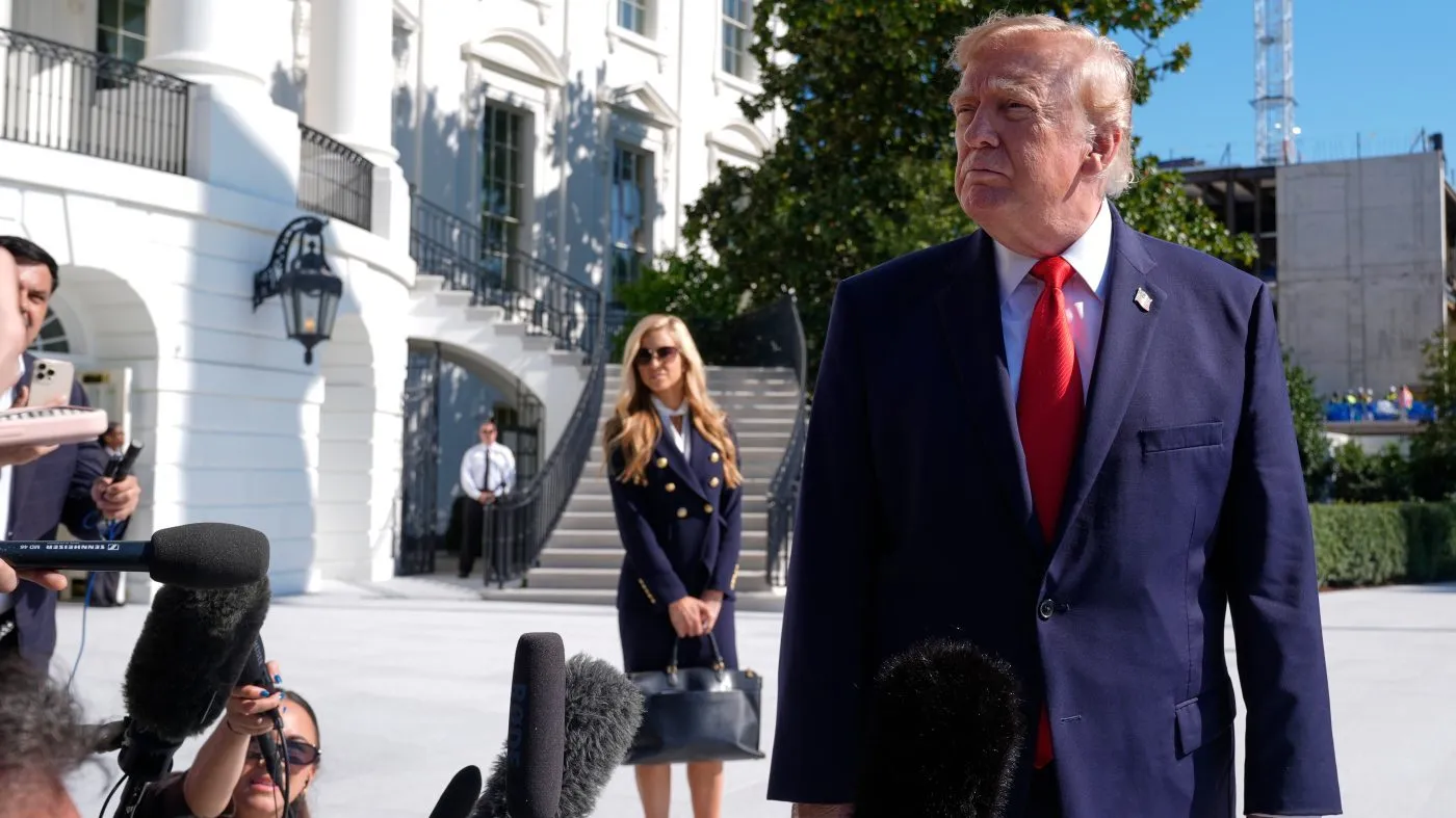 President Donald Trump talks to reporters before boarding Marine One, as White House press secretary Katie Zacharia looks on, on the South Lawn of the White House, Tuesday, Oct. 13, 2026, in Washington. (AP Photo/Manuel Balce Ceneta)