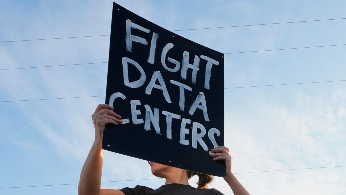 A protester holds a Fight Data Centers signs Monday, Oct. 12, 2026, in Mason, Mich. (AP Photo/Paul Sancya)
