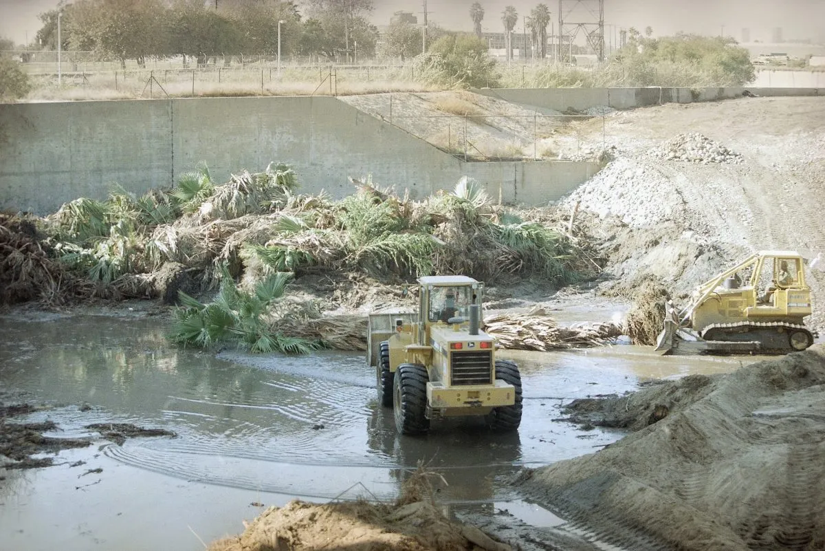 Bulldozers scoop up debris, including downed palm trees, along the Los Angels river bed, Wednesday, Oct. 29, 1997 in Glendale, Calif., as the Army Corps of Engineers started clear the riverbed. The Corp of Engineers, along with the County of Los Angeles, is completing flood control preparations for El Nino, which includes the removal of accumulated sediment, vegetation and debris from the 95 flood control facilities along the Los Angeles River and flood channels across the county. (AP Photo/Damian Dovarganes)