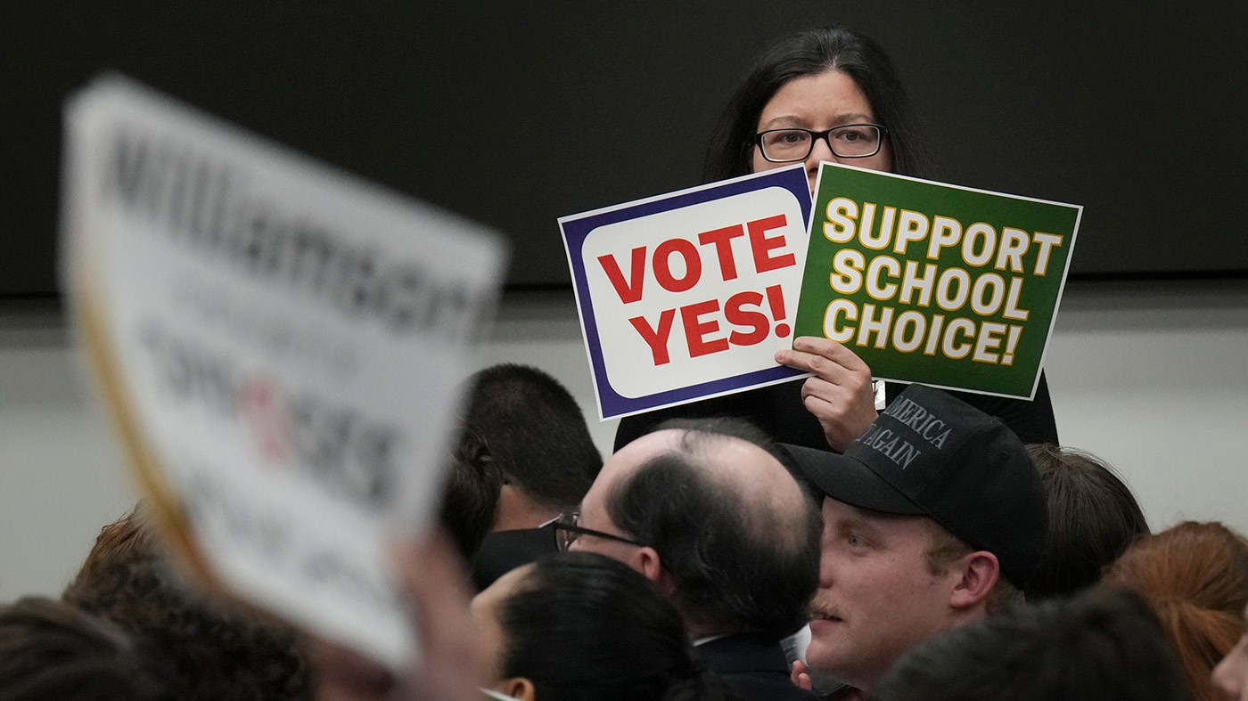 Penelope Koutoulas holds signs supporting school choice in a House committee meeting on education during a special session of the state Legislature on Jan. 28, 2025, in Nashville, Tenn.