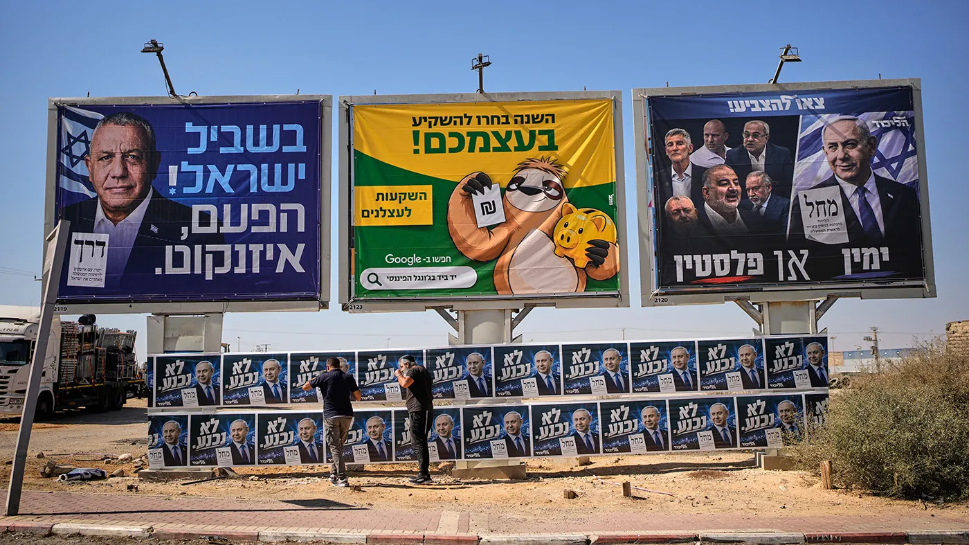 Likud activists hang campaign posters of Israeli Prime Minister Benjamin Netanyahu beside a billboard featuring opposition rival Gadi Eisenkot ahead of Israel’s general election in Dimona, southern Israel, Wednesday, Oct. 21, 2026.