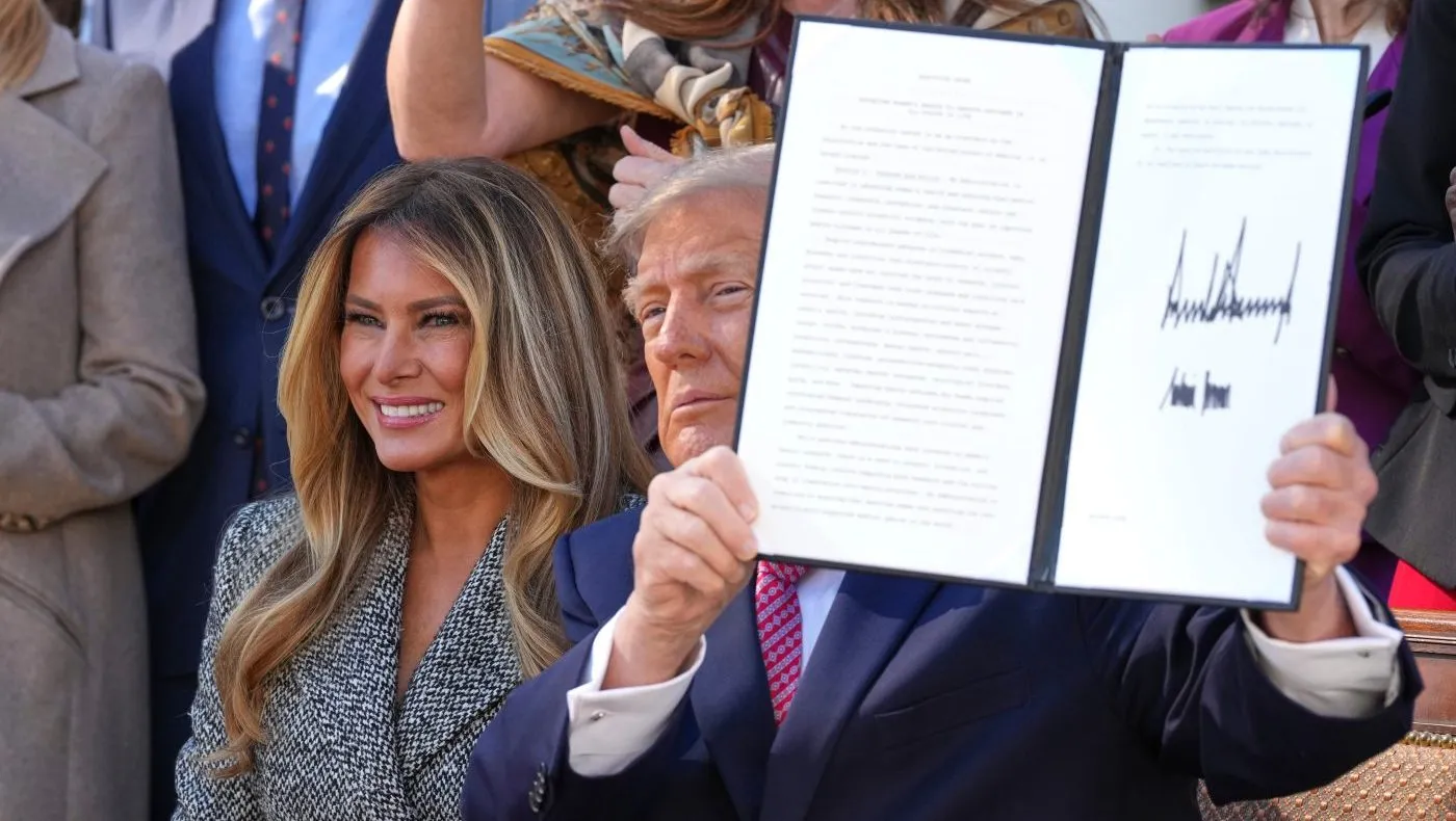 President Trump holds up a signed executive order alongside first lady Melania Trump at an event about women’s health, in the Rose Garden of the White House, Oct. 19, 2026, in Washington.