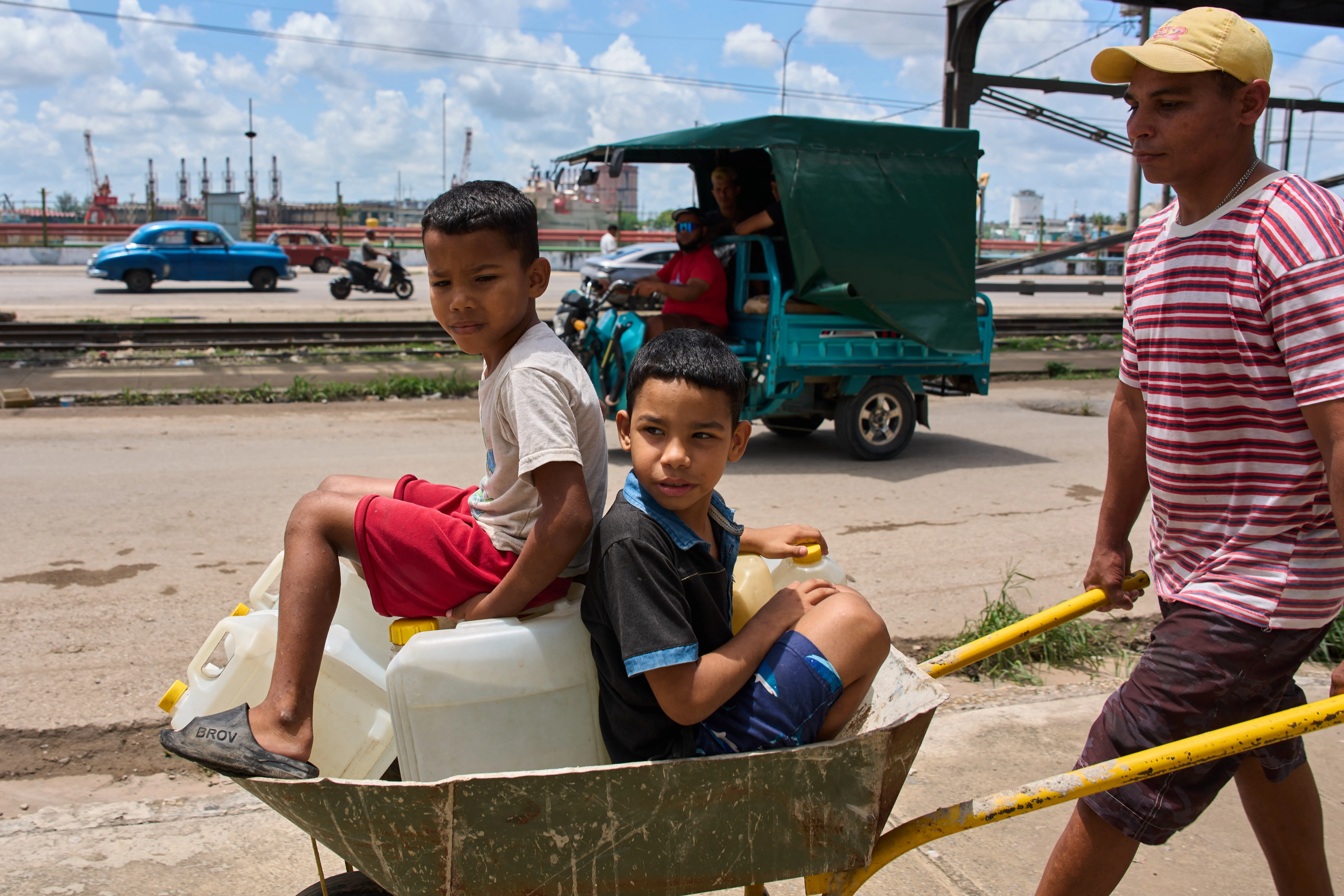 A man transports containers of water with his children in Havana, Thursday, May 28, 2026. (AP Photo/Ramon Espinosa)