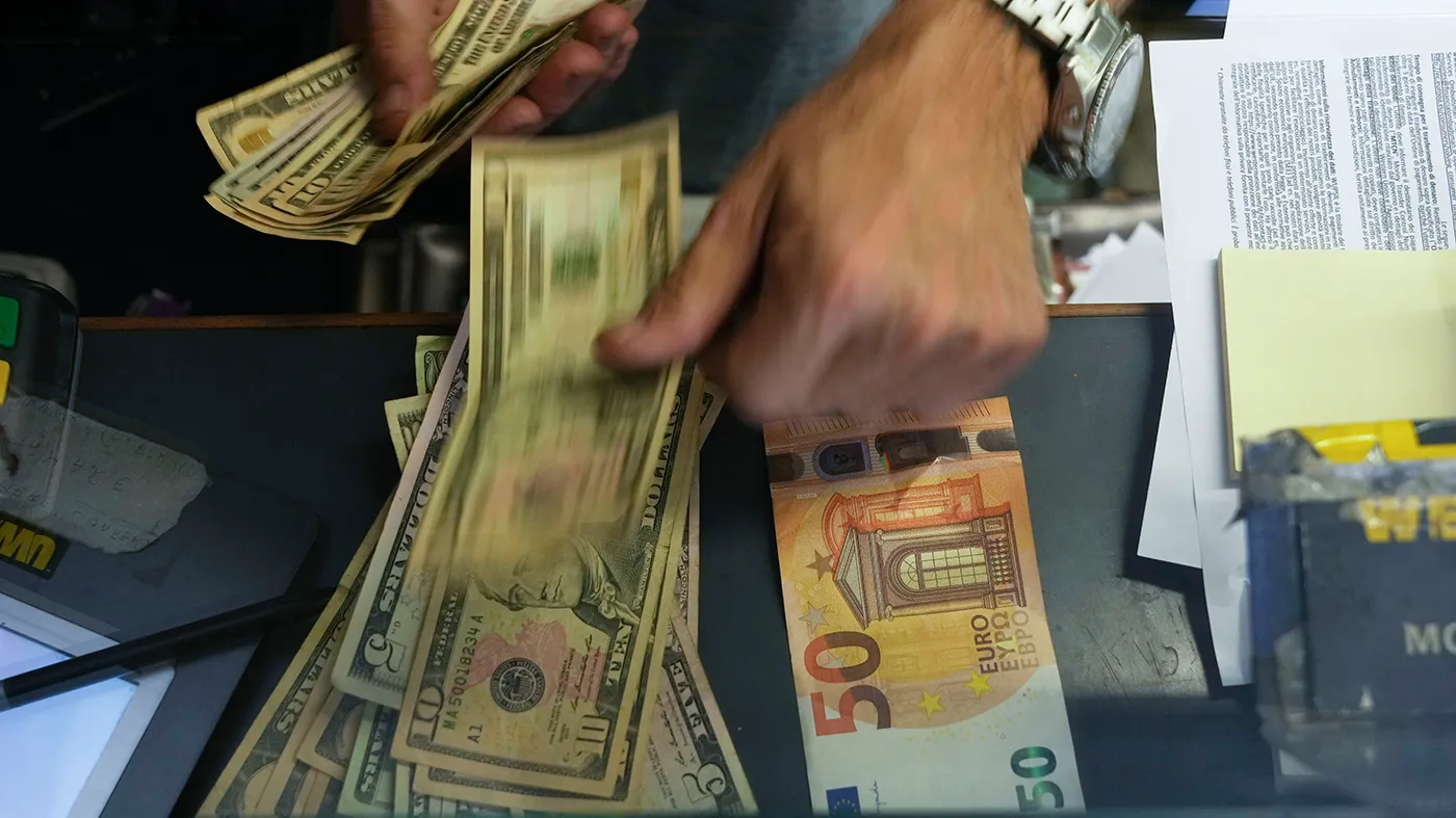 A cashier changes a 50 Euro banknote with U.S. dollars at an exchange counter in Rome. Inflation for the countries using the euro currency hit another record in August, fueled by soaring energy prices mainly driven by Russia’s war in Ukraine.