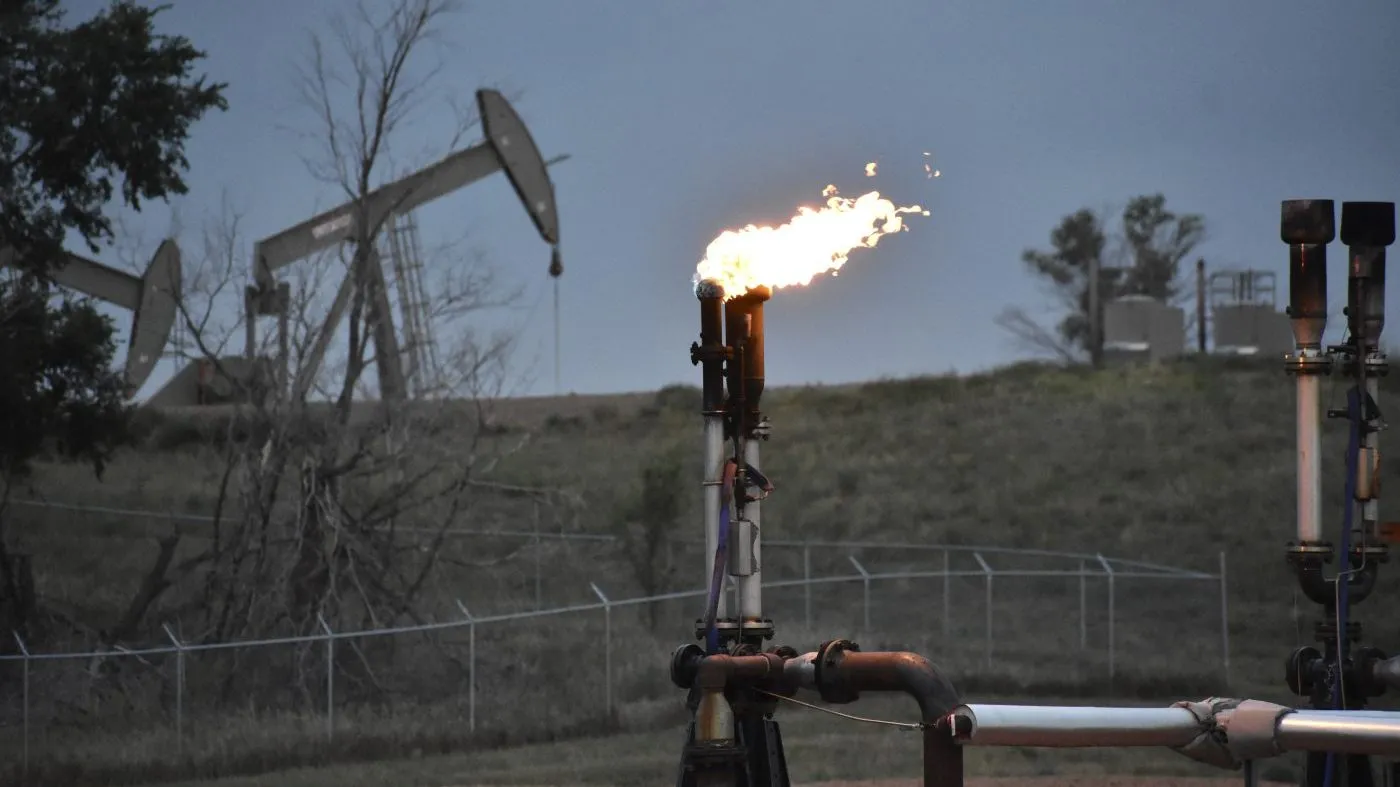 A flare to burn methane from oil production is seen on a well pad near Watford City, N.D., on Aug. 26, 2021.