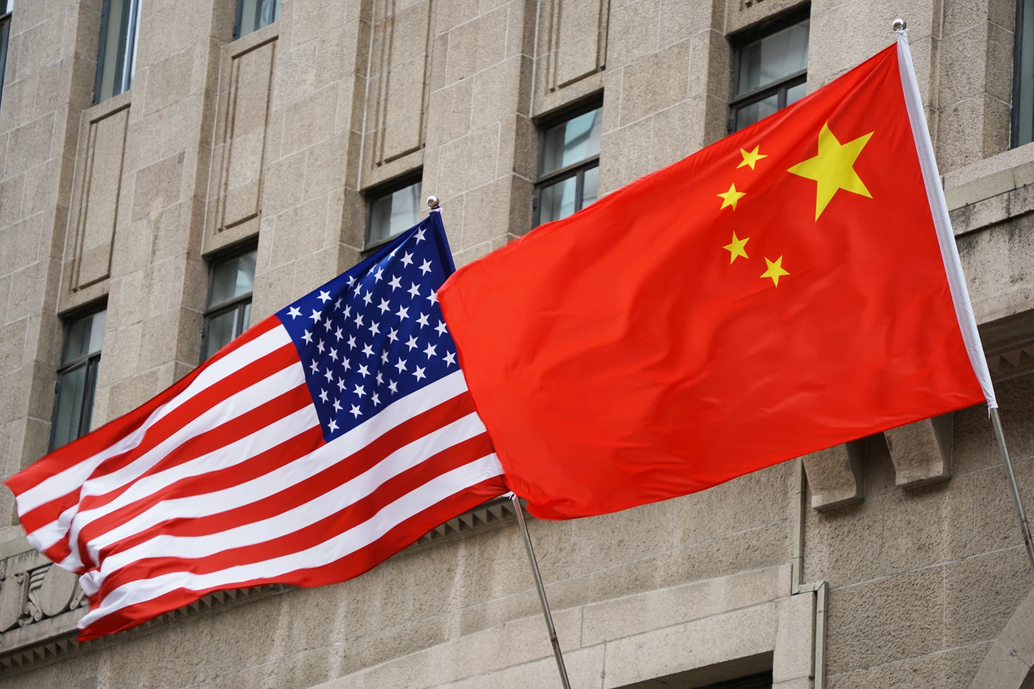 The national flags of the United States and China flutter at the Fairmont Peace Hotel on April 25, 2024 in Shanghai.