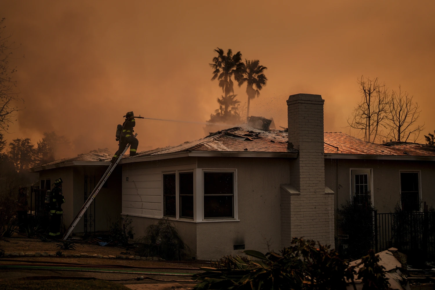 Fire crews battle the Eaton Fire as it impacts a structure on Jan. 9, 2025, in Altadena, Calif.