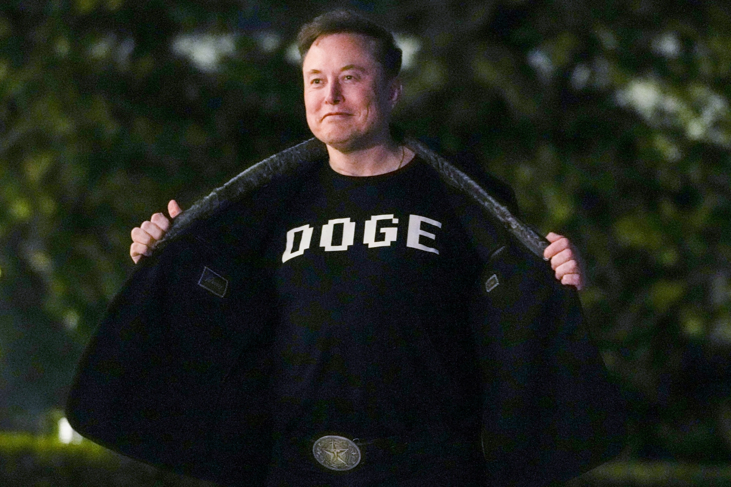 Elon Musk shows off a shirt that says "DOGE" as he walks on the South Lawn of the White House on March 9, 2025.