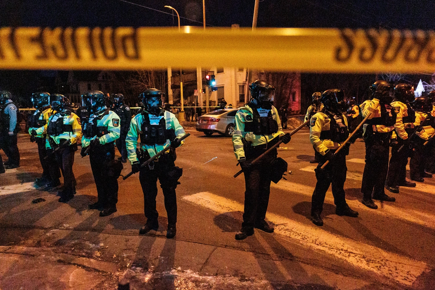 Law enforcement officers guard the perimeter of the scene as residents protest a federal agent-involved shooting during an immigration enforcement operation in Minneapolis on Jan. 14, 2026.