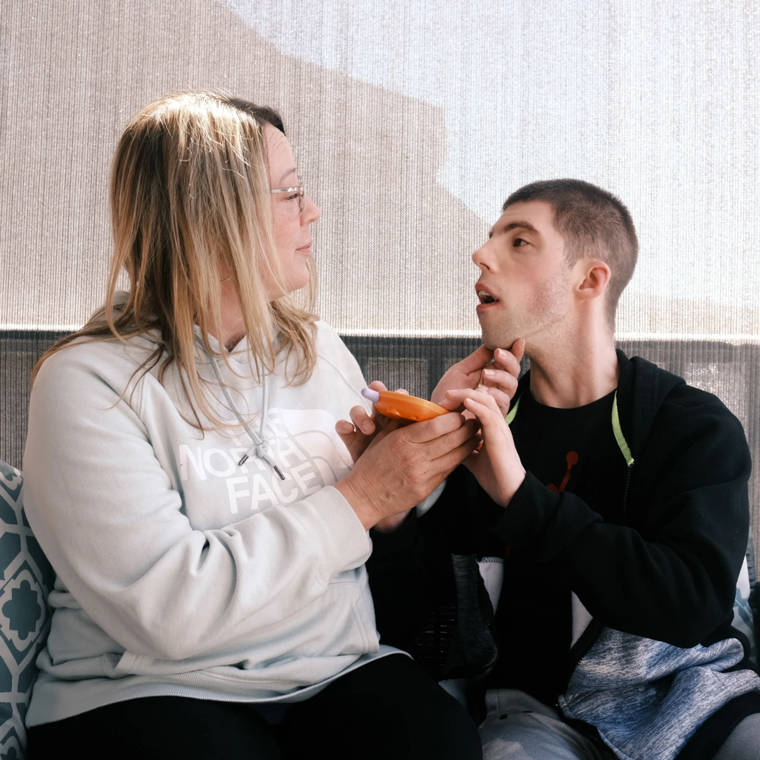 Melissa Gonce, a mother outside Baltimore, cares for her 28-year-old son, Jason, who has a rare chromosome disorder and requires constant supervision, on May 4, 2026. Gonce entered a self-directed Medicaid program that allows her to be paid as his caregiver after struggling with unreliable outside care. Proposed Medicaid cuts could reduce her income by more than $20,000 a year, forcing difficult decisions about her son’s care. (Kyna Uwaeme for NBC News)