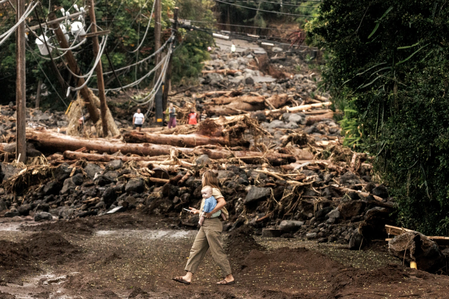 A woman and child walk past a debris-strewn street after Hurricane Lala in Naalehu, Hawaii, Monday, Aug. 17, 2026. 