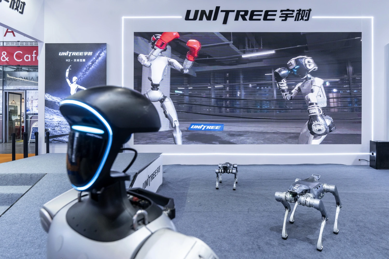 A Unitree Robotics G1 humanoid robot and Unitree Robotics As2 robot dogs on display at the company's booth during the Embodied Intelligent Robot Industry Exhibition in Shanghai, China, on Wednesday, Aug. 12, 2026. 